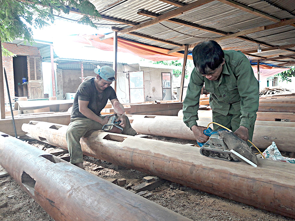 Hai thợ mộc Nguyễn Văn Hồng (trái) và Nguyễn Văn Kính thực hiện công đoạn chà nhám cột nhà tại cơ sở gỗ Thành Tỷ.