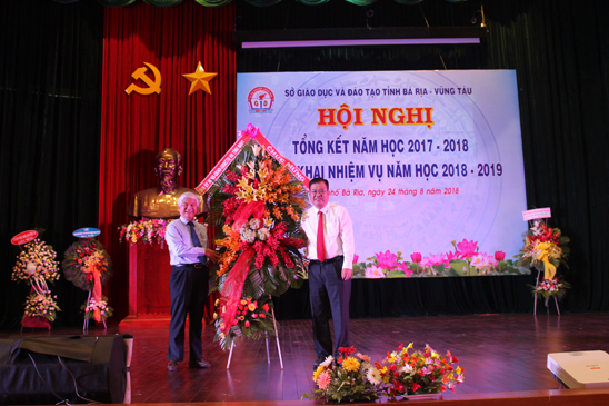 Đồng chí Nguyễn Văn Trình, Chủ tịch UBND tỉnh trao lẵng hoa chúc mừng của Tỉnh ủy, HĐND, UBND, UBMTTQVN tỉnh đến ngành GD-ĐT tại hội nghị.