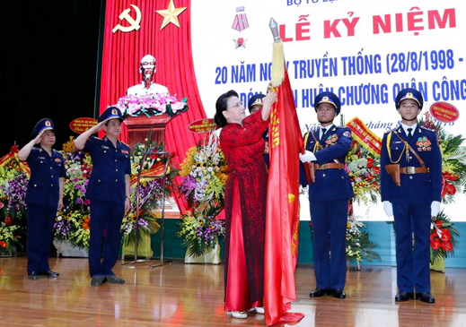 Chủ tịch Quốc hội Nguyễn Thị Kim Ngân gắn Huân chương Quân công hạng Ba  lên lá cờ truyền thống của lực lượng Cảnh sát biển Việt Nam.  