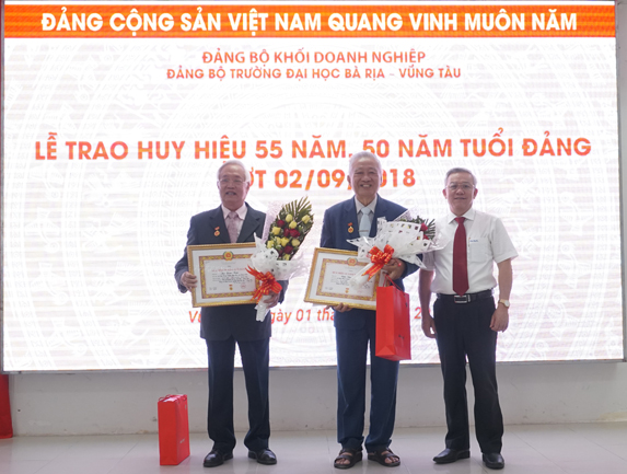 Đồng chí Hoàng Minh Kim, Phó Bí thư Đảng ủy khối Doanh nghiệp trao Huy hiệu 55 năm tuổi Đảng cho đảng viên Trần Văn Khánh (giữa) và Huy hiệu 50 năm tuổi Đảng cho đảng viên Mai Xuân Thiệu.