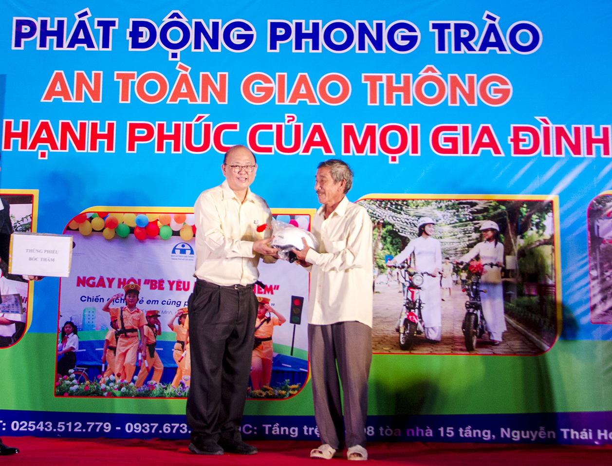 Ông Prasert Pharttanarsatarporn (trái), Giám đốc An toàn Công ty TNHH Hóa dầu Long Sơn (LSP), trao mũ bảo hiểm cho người dân Long Sơn.