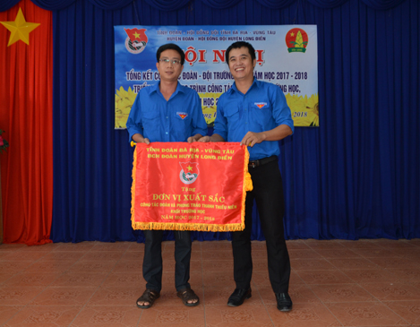Anh Trần Kim Chỉ (bìa phải), Trưởng Ban Thanh thiếu nhi – Trường học, Tỉnh Đoàn trao cờ thi đua của Huyện Đoàn Long Điền cho các tập thể có thành tích xuất sắc trong công tác Đoàn, Đội năm học 2017-2018.