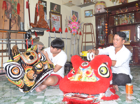 Anh Huỳnh Thế Phương (phải) và anh Nguyễn Thanh Nam, thành viên CLB lân-sư-rồng Hùng Nghĩa Đường làm đầu lân chuẩn bị phục vụ mùa Trung thu. Ảnh: CẨM NHUNG