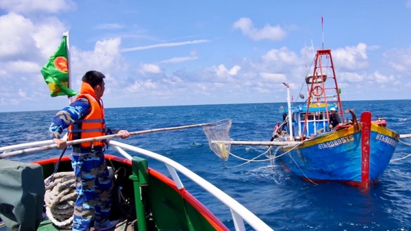 Lực lượng chức năng tiếp cận tàu cá, phát tờ rơi tuyên truyền về bảo vệ công trình dầu khí cho ngư dân.