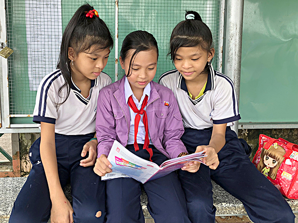 Em Bùi Thị Gia Hân, HS lớp 5/3, Trường Tiểu học Nguyễn Công Trứ  (giữa) cùng các bạn ôn bài trong lúc chờ cha mẹ đón tại “Nhà chờ HS”. 