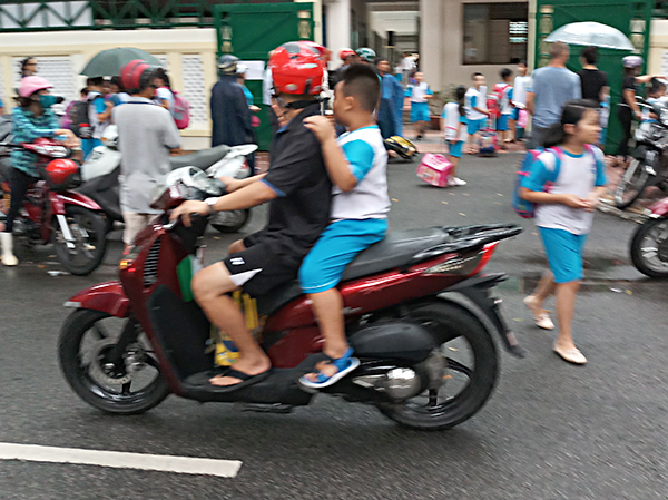 Một phụ huynh chưa có ý thức bảo vệ an toàn cho con mình khi đi xe máy mà không đội mũ bảo hiểm.
