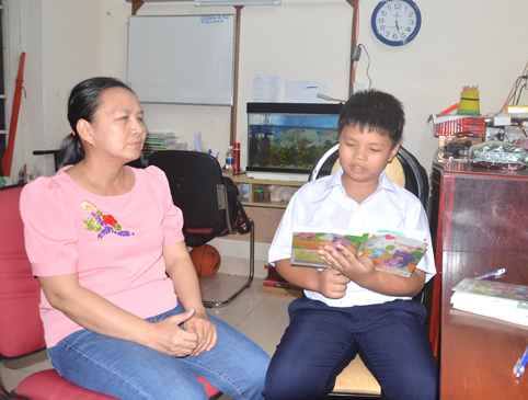 Chị Trang nghe con trai Nguyễn Thành Tài đọc bài từ sách giáo khoa.