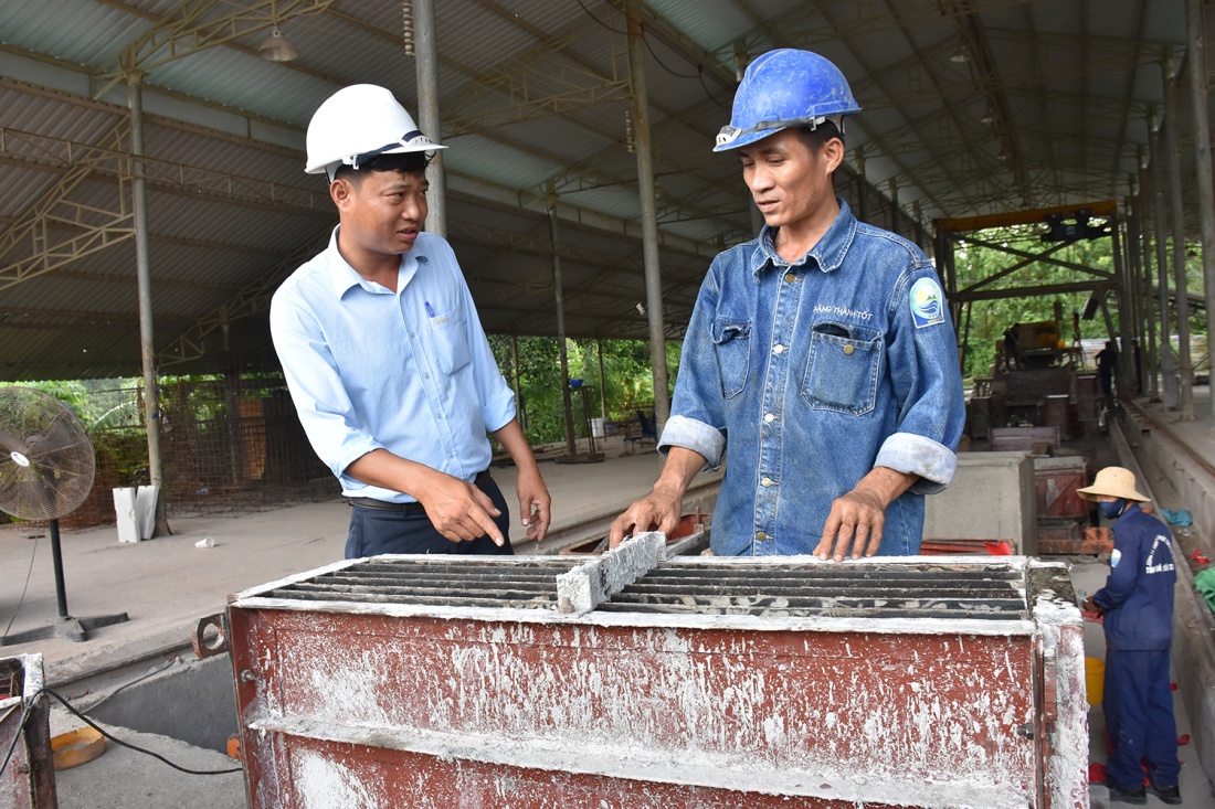 Anh Nguyễn Văn Tự (trái) trao đổi với công nhân về tấm đan lắp trên các hố ga không mùi.