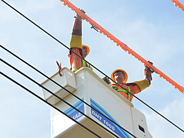 Công nhân đội sửa chữa điện hotline che chắn, bọc đường dây điện 22kV bằng ống nhựa cách điện trước khi sửa chữa. Ảnh: CẨM NHUNG