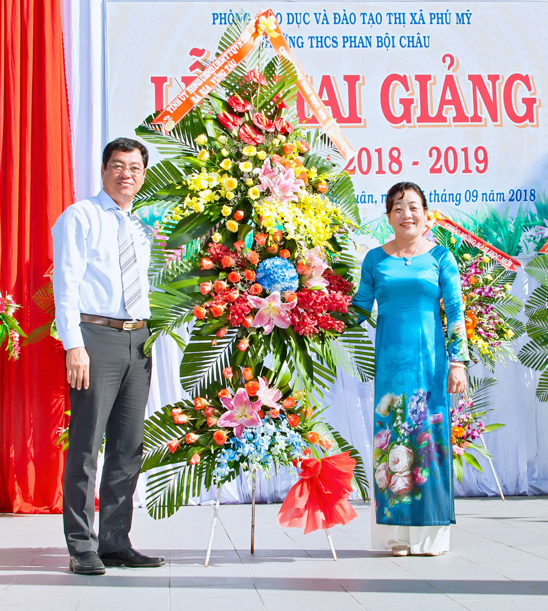 Đồng chí Trần Đình Khoa, Ủy viên Ban Thường vụ Tỉnh ủy, Phó Chủ tịch HĐND tỉnh trao lẵng hoa chúc mừng của Tỉnh ủy, HĐND, UBND, UBMTTQVN tỉnh cho  cô Nguyễn Thị Phi Long và Trường THCS Phan Bội Châu nhân ngày khai giảng  năm học mới 2018-2019.