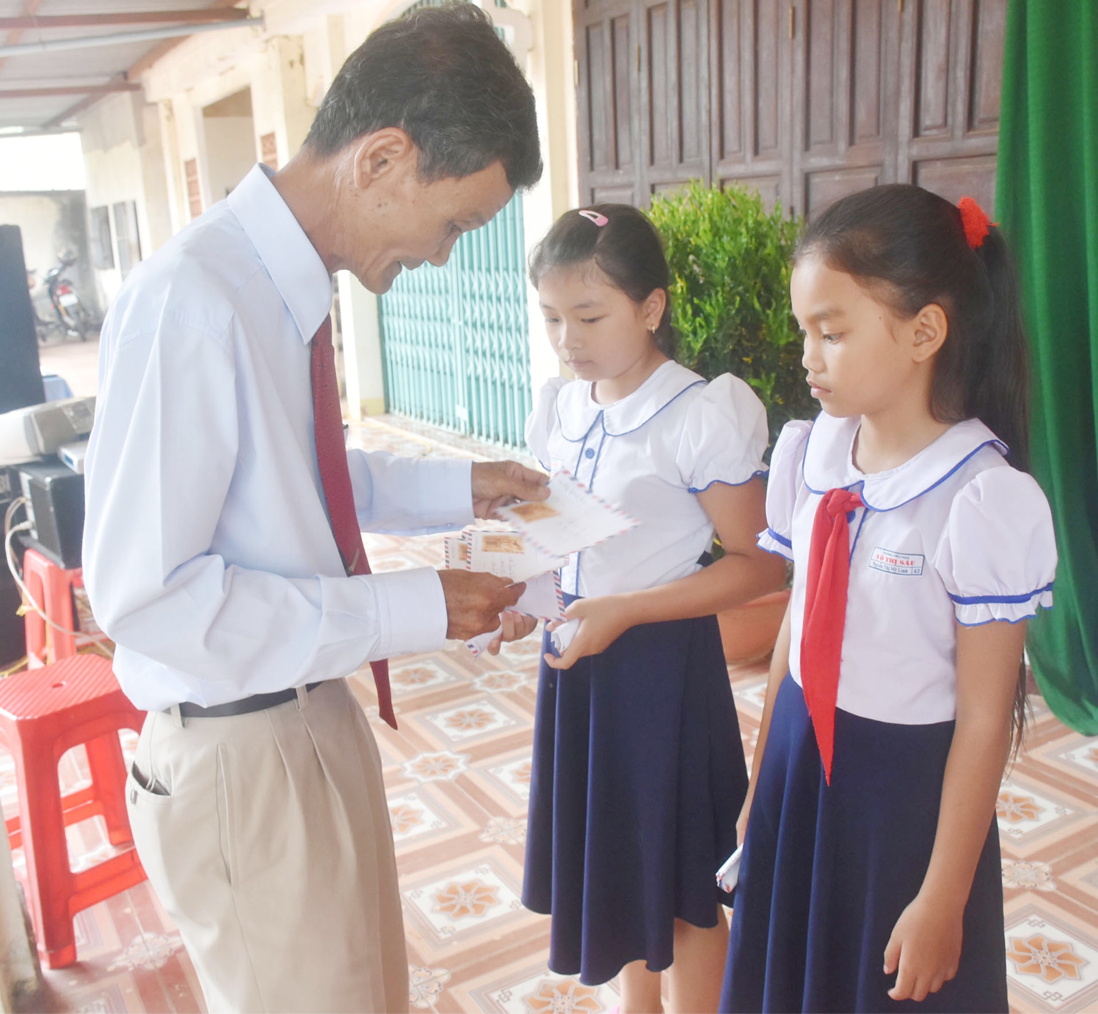 Đại diện UBND thị trấn Đất Đỏ tặng quà cho các HS nghèo vượt khó học giỏi tại khu phố Phước Trung. Ảnh: TRÍ NHÂN