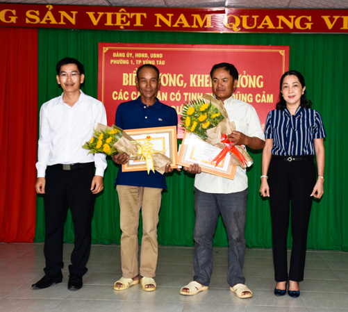 Ông Hà Hữu Dũng, Chủ tịch UBND phường 1 (bìa trái) và bà Võ Thanh Mỹ, Bí thư Đảng ủy phường 1 tặng hoa và giấy khen biểu dương hành động dũng cảm của anh Nguyễn Thế Lộc và anh Doãn Cao Cường.