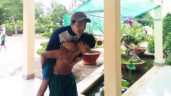 Đang dở tay làm vườn, thấy bà con đến trú bão, binh nhất Lê Minh Tùng, chiến sĩ Đồn Biên phòng Chí Linh bỏ cuốc chạy đến cõng người khuyết tật ở khu phố 3, phường 10 vào phòng trú bão.
