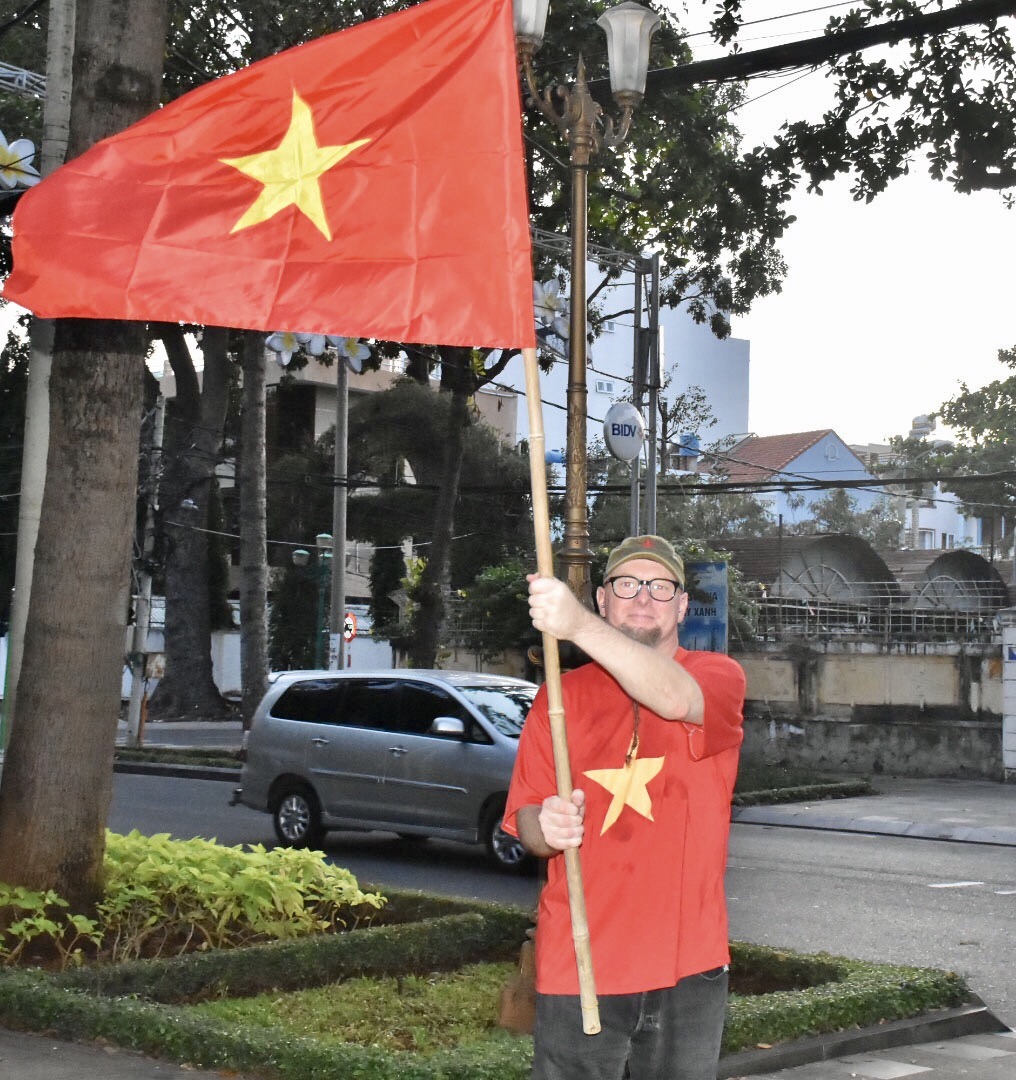 Một du khách người Úc mặc áo và mang cờ Việt Nam trên đường Trần Hưng Đạo, TP.Vũng Tàu chiều 11-12. Ảnh: THÀNH HUY