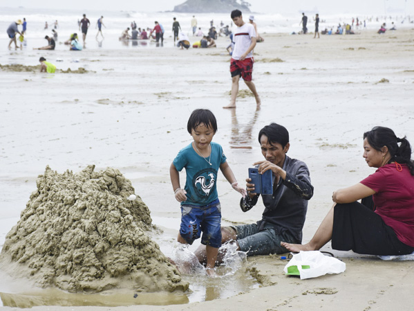 Du khách chơi đắp cát trên Bãi Sau. Ảnh: ĐĂNG KHOA