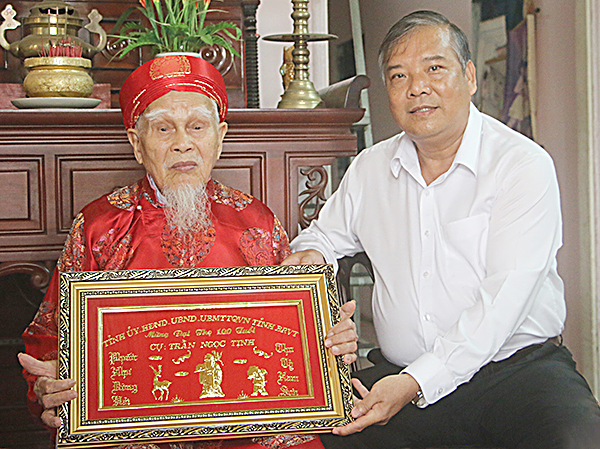 Đồng chí Bùi Thanh Nghĩa, Ủy viên Ban Thường vụ Tỉnh ủy, Chủ tịch UBMTTQ Việt Nam tỉnh trao khánh vàng cho cụ Trần Ngọc Tịnh (phường Phú Mỹ, TX. Phú Mỹ).  Ảnh Bùi Hương.