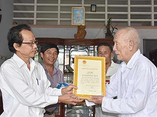 Đồng chí Phạm Thế Mỹ, Phó Chủ tịch UBMTTQVN tỉnh trao thiếp mừng thọ 100 tuổi của Chủ tịch nước cho cụ ông Lê Bình (100 tuổi) ở xã Bình Châu, huyện Xuyên Mộc. Ảnh: THÀNH HUY