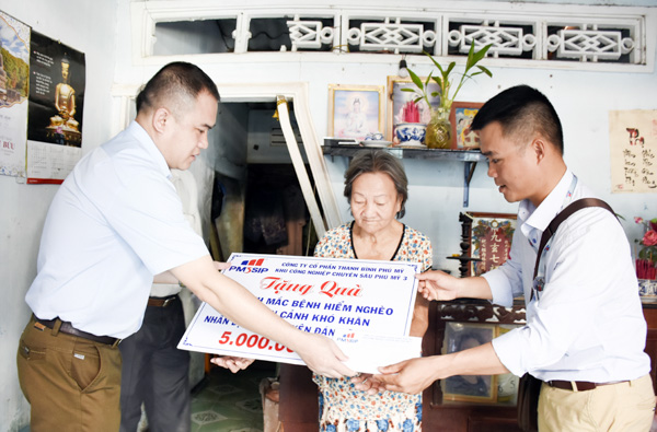 Đại diện Công ty CP Thanh Bình-Phú Mỹ, chủ đầu tư KCN Phú Mỹ 3 trao bảng tượng trưng số tiền 5 triệu đồng cho bà Nguyễn Thị Bảo Anh (thôn Phước Long, xã Tân Hòa) - người già mất sức lao động đang phải chăm sóc chị bị liệt toàn thân. 