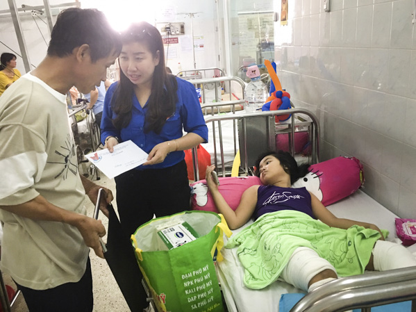 Chị Trần Thị Lan, Phó Bí thư Thị Đoàn Phú Mỹ trao tiền cho người thân em Vũ Thị Hồng. 