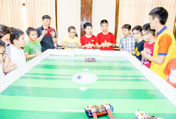 Các thí sinh tập dợt điều khiển robot đá bóng tại buổi tập huấn.