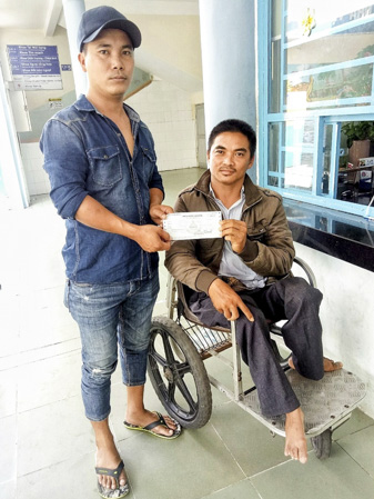 Anh Trần Văn Dương (bìa trái), Trưởng nhóm thiện nguyện Phúc Duyên trao biên lai đóng tiền viện phí điều trị phỏng cho anh Lê Văn Bình, chú ruột em Lê Gia Huy. Ảnh: PHÚC DUYÊN