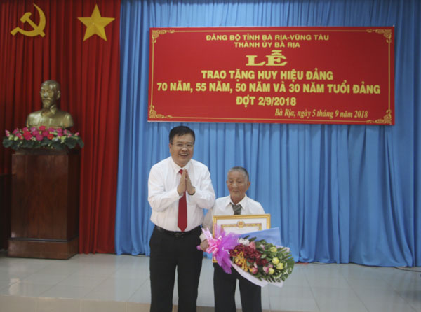 Đồng chí Nguyễn Văn Trình, Phó Bí thư Tỉnh ủy, Chủ tịch UBND tỉnh trao Huy hiệu 70 năm tuổi Đảng cho đồng chí Phan Viết Thành (Đảng bộ phường Phước Nguyên, TP.Bà Rịa) dịp 2-9-2018.