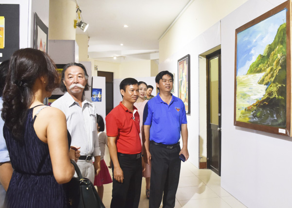  Khách tham quan và trao đổi về các bức tranh tại khu vực triển lãm.
