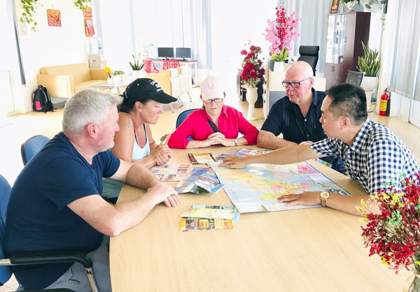 Nhân viên Trung tâm Hỗ trợ khách du lịch TP. Vũng Tàu giới thiệu các điểm du lịch trên địa bàn  TP. Vũng Tàu qua bản đồ cho nhóm du khách người Áo ngày 3-6. Ảnh: H.T
