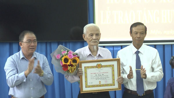 Ông Nguyễn Văn Thọ, Bí thư Huyện ủy (bìa phải) và ông Đặng Thanh Minh, Chủ tịch UBND huyện Xuyên Mộc (bìa trái) trao huy hiệu 70 năm tuổi Đảng cho đảng viên Bùi Quang Hãn, chi bộ khu phố Thanh Sơn, Đảng bộ thị trấn Phước Bửu.