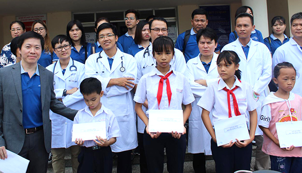 Ông Jason Chong (bìa phải), Phó Tổng Giám đốc International SOS  tặng học bổng cho HS nghèo vượt khó, học giỏi.