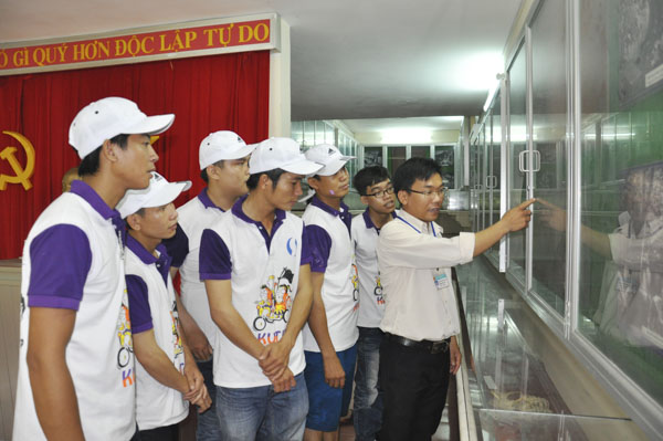 Du khách nghe giới thiệu về các hiện vật tại Phòng truyền thống khu di tích căn cứ cách mạng Minh Đạm. Ảnh: MINH THANH