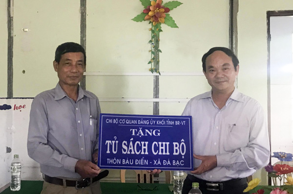Ông Chu Văn Tiến, Phó Bí thư Đảng ủy Khối Cơ quan tỉnh (bên phải) trao bảng tủ sách tượng trưng cho Chi bộ thôn Bàu Điển, xã Đá Bạc.