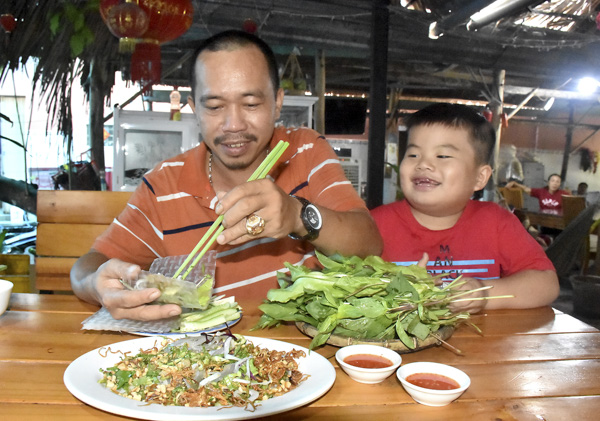 Anh Trần Phúc Linh - chủ quán gỏi cá đục Như Linh hướng dẫn cách cuốn gỏi cá đục vào bánh tráng.
