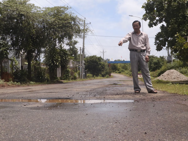 Ông Lê Quang Cạnh, Trưởng ấp Tiến Thành, xã Quảng Thành đứng bên một địa điểm mặt đường khu dân cư của ấp bị hư hỏng nơi tiếp giáp với tuyến đường liên xã Quảng Thành - Bàu Chinh - Bình Giã.