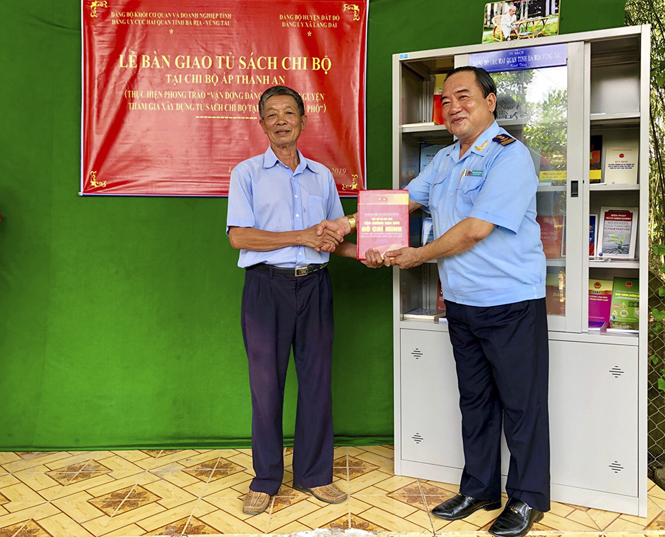 Ông Trần Văn Danh, Bí thư Đảng ủy, Cục trưởng Cục Hải quan tỉnh (bên phải) bàn giao tủ sách cho Chi bộ ấp Thanh An thuộc Đảng ủy xã Láng Dài (huyện Đất Đỏ).