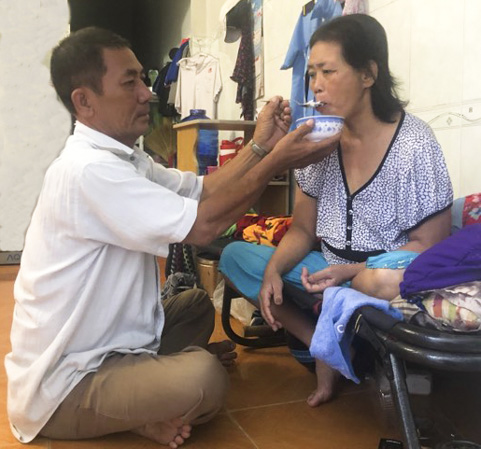 Ông Võ Phát Giàu đút cơm cho vợ bị liệt và mù lòa.