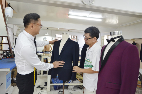 Anh Nguyễn Văn Hoàng, chủ nhà may Hồng Phát và thợ kỹ thuật kiểm tra bộ suit trước khi hoàn thiện công đoạn cuối để giao khách. Ảnh: MINH THANH