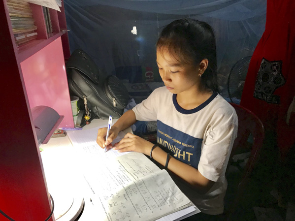 Bé Thủy tranh thủ làm bài tập sau khi giúp cha lo việc nhà.