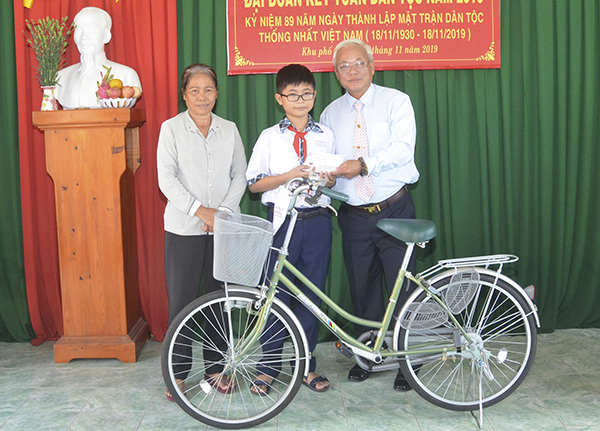 Ông Trần Hữu Đức, đại diện Ban Tế tự chùa Ông Quan Thánh và Lăng ông Nam Hải tặng xe đạp và học bổng vượt khó học giỏi (tổng trị giá 5 triệu đồng) cho em Nguyễn Đoàn Anh Kiệt, lớp 6A6, Trường THCS Nguyễn Du, phường Phước Trung. Ảnh: NGUYỄN ĐỨC