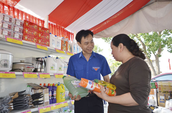 Anh Huỳnh Công Luận, nhân viên Siêu thị Co.op Mart Phú Mỹ giới thiệu những mặt hàng thiết yếu cho khách tại gian hàng giảm giá của thanh niên trong Ngày hội “Xuân ấm áp-Tết yêu thương”.