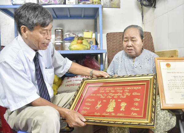 Ông Trần Đức Lục, Phó Ban đại diện Hội Người cao tuổi tỉnh trao khánh vàng cho cụ Nguyễn Thị Chu (ở 167/1A Bacu, phường 4, TP. Vũng Tàu). Ảnh: TRẦN TRÀ
