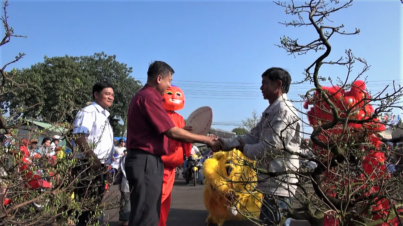 Ông Phan Thiên Khiêm (bên trái), Trưởng Ban Quản lý chợ Ngãi Giao chúc các tiểu thương năm mới buôn bán được thuận lợi.