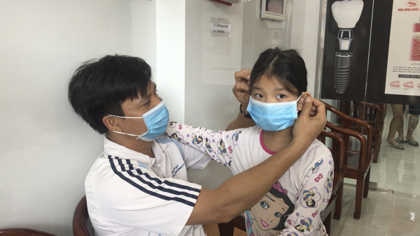 Sử dụng khẩu trang và rửa tay bằng xà bông đúng cách là một trong những biện pháp phòng bệnh Corona hiệu quả. Trong ảnh: Khách hàng đeo khẩu trang y tế khi đến khám răng tại Nha khoa Quốc Bình, TP.Vũng Tàu. Ảnh: ĐỨC TIỆN 