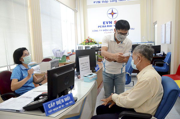 Nhân viên Điện lực TP. Vũng Tàu phát khẩu trang  và đo thân nhiệt cho khách hàng đến giao dịch. 