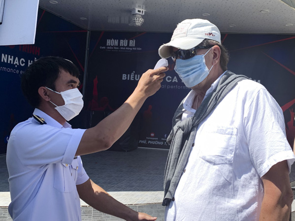 Nhân viên Công ty TNHH Công nghệ xanh DP (Greenlines DP) chi nhánh Vũng Tàu đo thân nhiệt cho khách nước ngoài  trước khi xuống tàu. Ảnh: THANH NGA