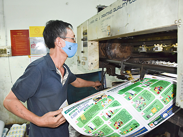 Công nhân Xí nghiệp In tổng hợp Vũng Tàu kiểm tra bài in Poster “An toàn giữa mùa dịch COVID-19”  phát hành ngày 26/3. Ảnh: QUANG VINH