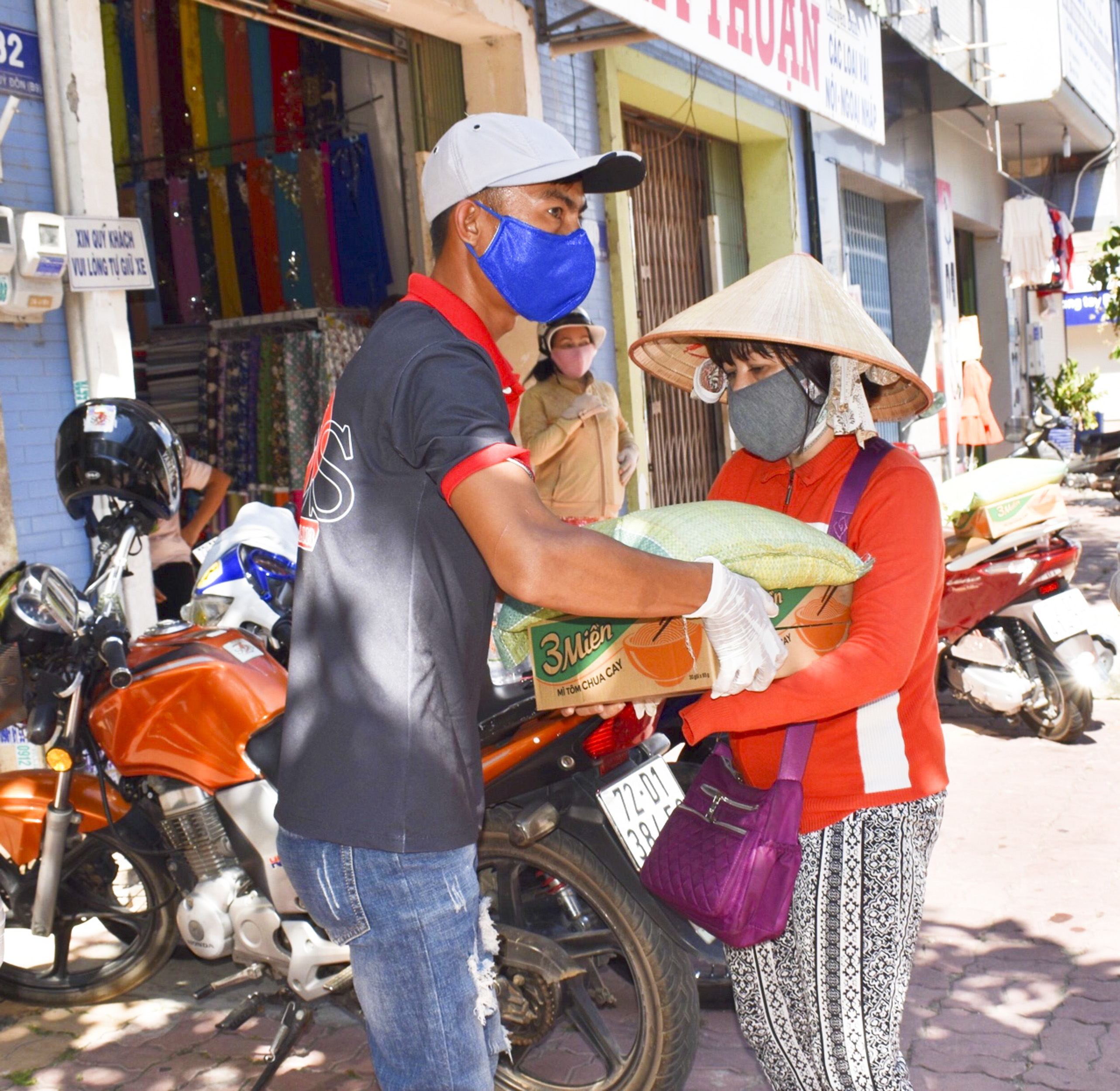 Các tình nguyện viên nhóm SOS 72 Bà Rịa hỗ trợ anh Phúc trao tặng gạo và mì gói cho người bán vé số trên địa bàn TP. Bà Rịa.