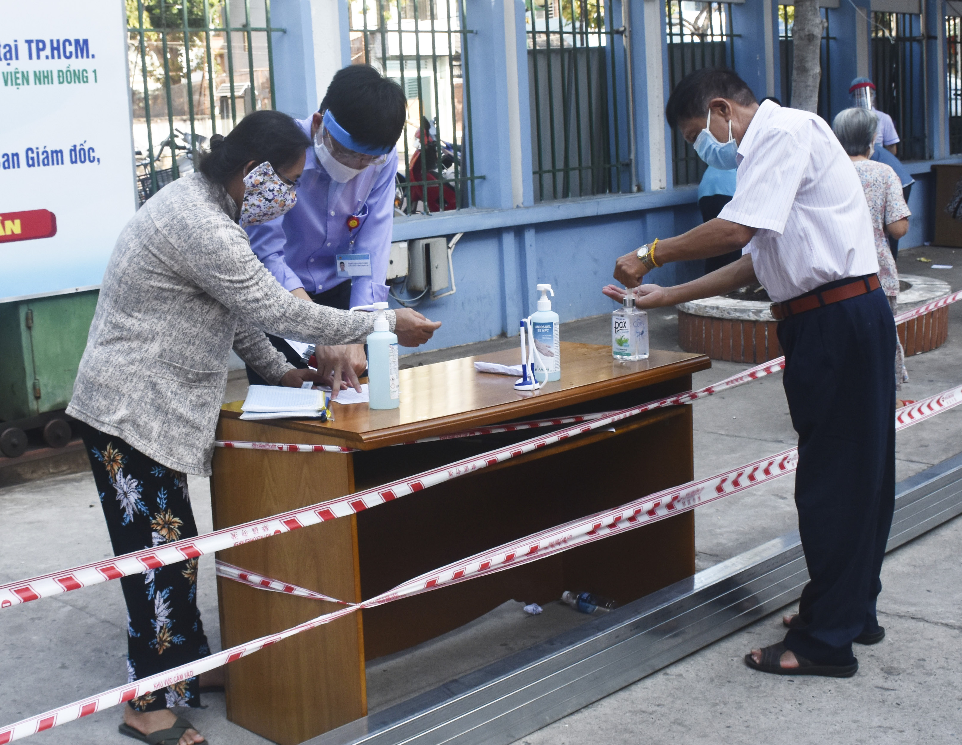 Nhân viên y tế hướng dẫn người đến BV khai báo y tế và yêu cầu sát khuẩn tay trước khi vào bệnh viện.