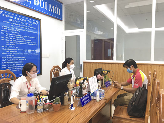 Công chức tại bộ phận một cửa Cục Thuế tỉnh tiếp nhận  hồ sơ thuế của người nộp thuế. Ảnh: MỸ PHƯƠNG