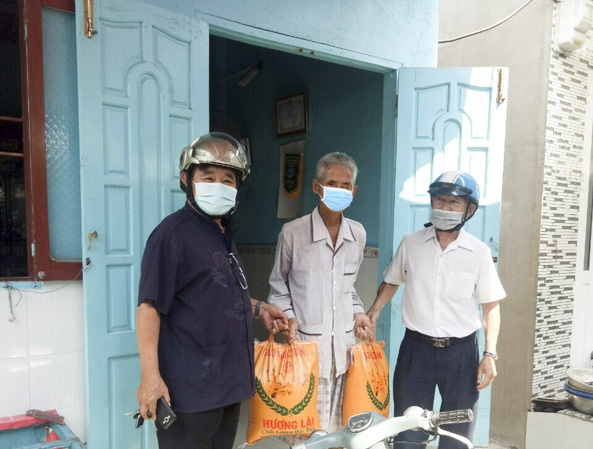 Ông Nguyễn Thành Sĩ (bìa phải) Chủ tịch Hội đồng hương QN- ĐN tặng gạo cho hộ khó khăn.